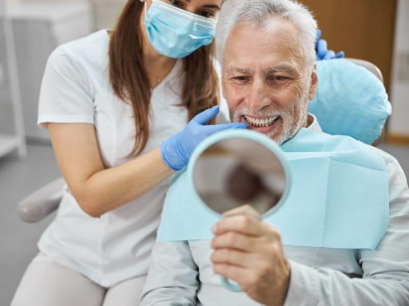 A senior patient admiring their dental implants in Arlington, TX